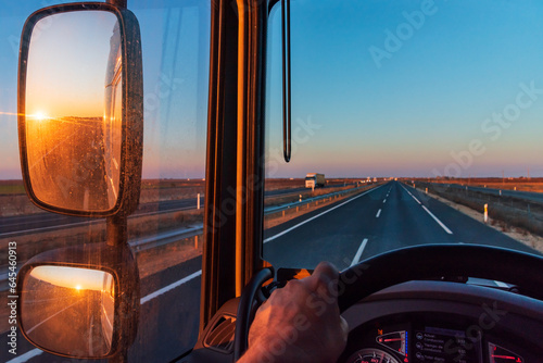 Foto View from the driver's seat of a truck, with a straight road ahead and the sun rising in the rearview mirror