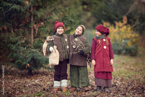 Children in the costumes of gnomes playing in the park with goose, fairy tale 