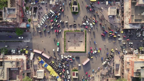Vertical Top angle aerial drone shot of the crossroads or roundabout with moving vehicles or traffic passing in a busy Indian city market or traditional old bazaar. Urban transportation concept