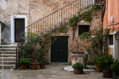 Una tipica corte veneziana con un pozzo, delle piante e una scala che sale al primo piano