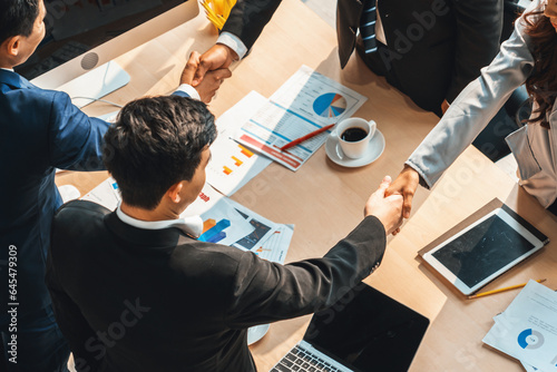 Group business people handshake at meeting table in office together with confident shot from top view . Young businessman and businesswoman workers express agreement of investment deal. Jivy