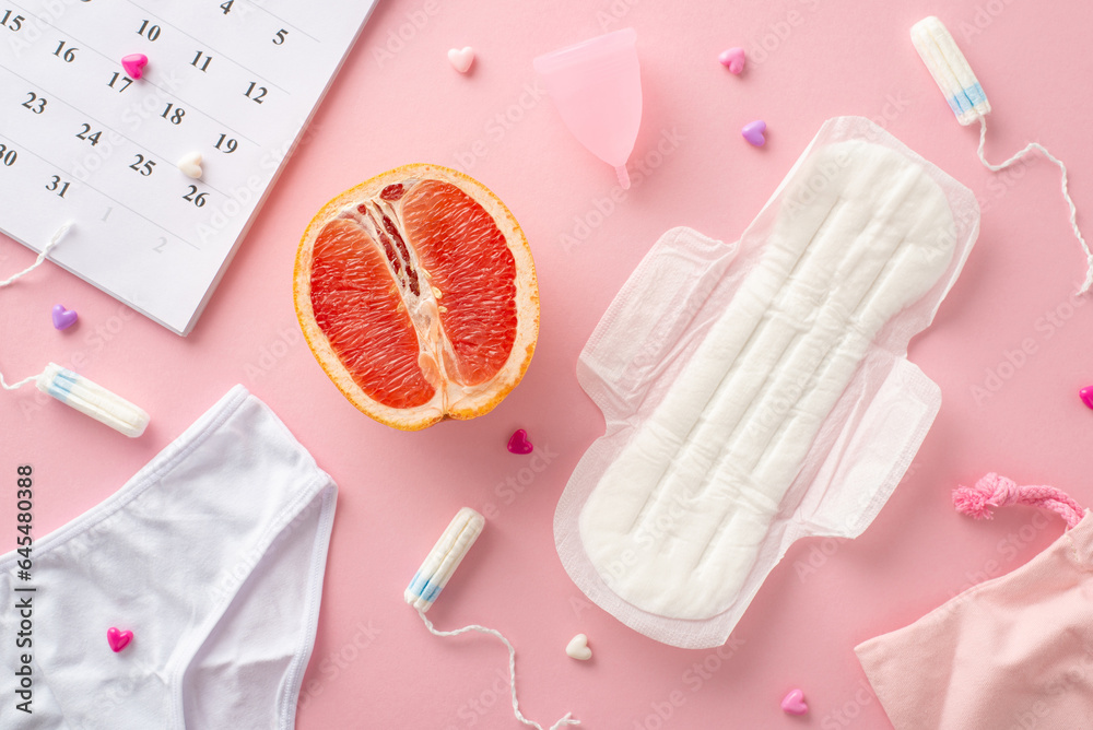Top view pastel pink scene featuring menstrual essentials such as pad, tampons, menstrual cup