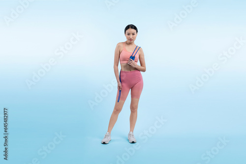 Young energetic asian woman in sportswear with jumping or skipping robe posing portrait in studio shot on isolated background. Cardio exercise tool and healthy body care lifestyle. Vigorous