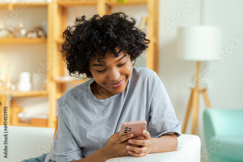 Photography African girl holding smartphone touch screen typing scroll page at home