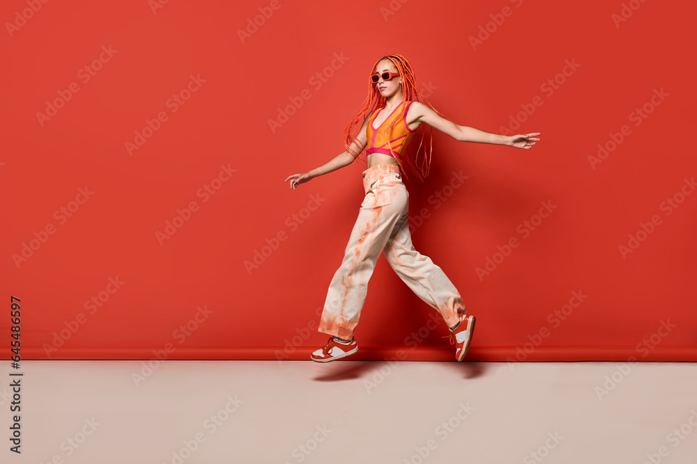 Stylish woman wearing sunglasses jumping in studio Stylish woman wearing sunglasses jumping in studio
