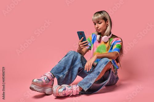 Young female hipster using smartphone in studio photo