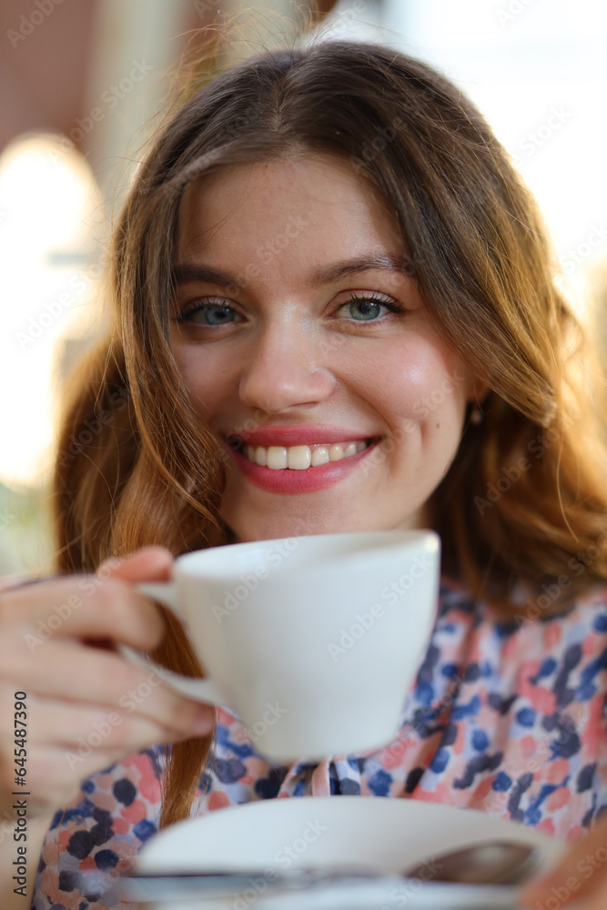 A happy and beautiful young woman enjoying a cup of coffee at a cafe, radiating cheerful and leisurely vibes in a city setting. A happy and beautiful young woman enjoying a cup of coffee at a cafe, radiating cheerful and leisurely vibes in a city setting.