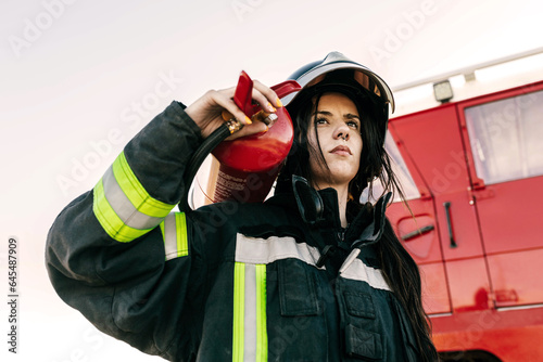 Brave female firefighter carrying fire extinguisher