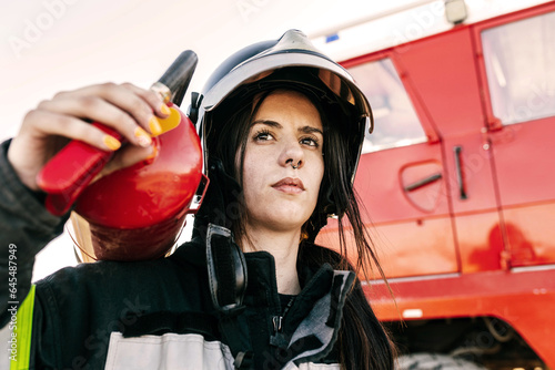 Brave female firefighter carrying fire extinguisher