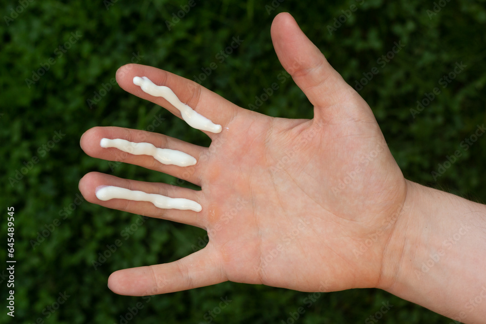 A person applying the correct amount of sunscreen for face and neck (three finger lengths).