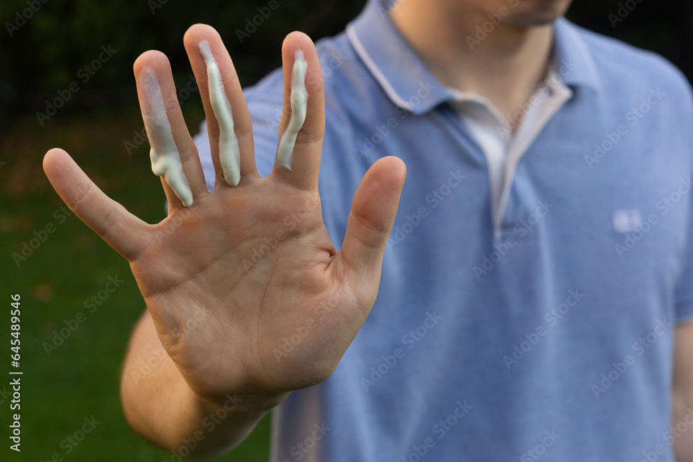 A man applying the correct amount of sunscreen for face and neck (three finger lengths).