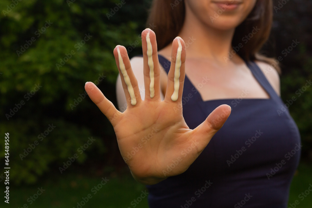 A woman applying the correct amount of sunscreen for face and neck (three finger lengths).