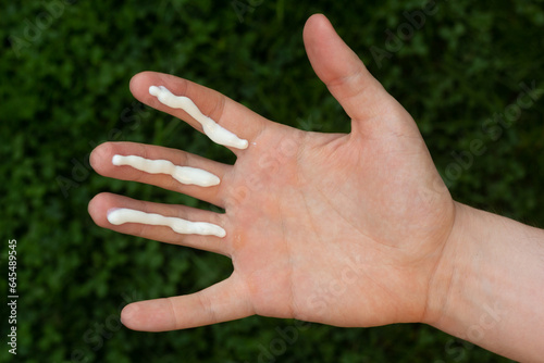 Obraz na płótnie A person applying the correct amount of sunscreen for face and neck (three finger lengths). w salonie