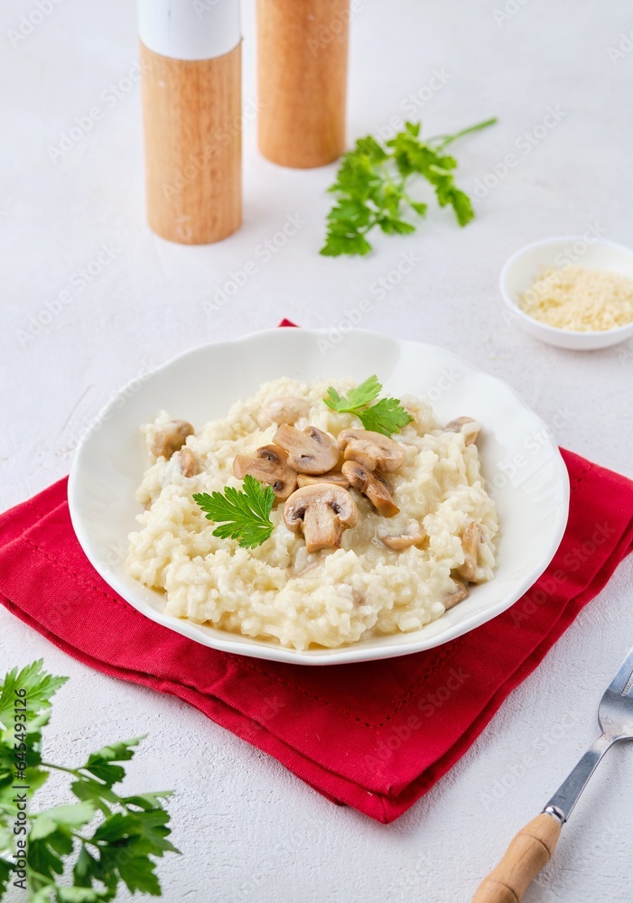 Risotto with mushrooms garnished with parsley in a light plate on a white concrete background. Risotto recipes. Risotto with mushrooms garnished with parsley in a light plate on a white concrete background. Risotto recipes.