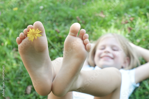 Child feet on green grass, barefoot little girl on meadow, countryside lifestyle, concept of grounding and connecting with nature photo