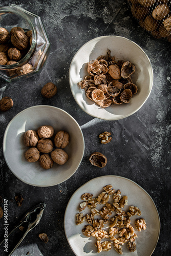 Walnut kernels and whole walnuts on dark stone table