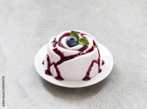 Foto Blueberry cream pudding, Panna Cotta with blueberry sauce, in the shape of a rose, on a plate