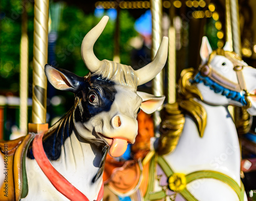 Canvas Print Colorful cow on traditional old french caroussel in city park in sunny day