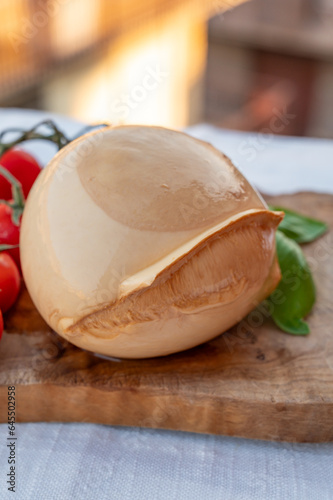 Ball of smoked Italian soft cheese Mozzarella di Bufala Campana served with fresh green basil and red sicilian tomatoes