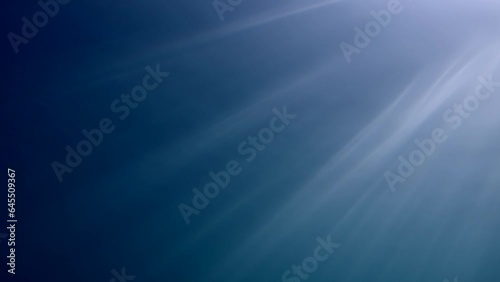 Diagonal sunrays under surface of water in the blue Ocean, Slow motion. The sun's rays penetrate underwater into the blue water through sea surface. Diagonal sunbeams underwater 
 photo