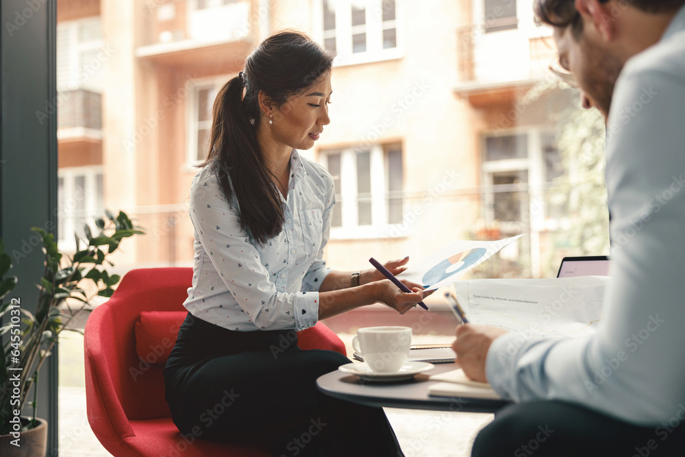 Fototapeta premium Two business colleagues working with documents together sitting in office.High quality photo
