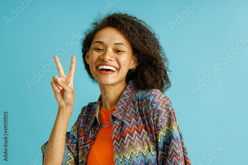 Happy woman standing over blue background smiling and doing victory sign with fingers