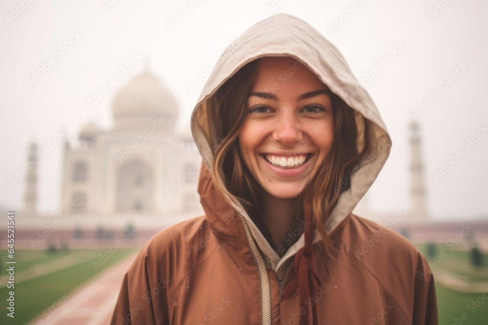 Close-up portrait photography of a pleased woman in her 20s that is wearing a warm parka in front of the Taj Mahal in Agra India Close-up portrait photography of a pleased woman in her 20s that is wearing a warm parka in front of the Taj Mahal in Agra India