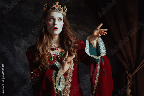 medieval queen in red dress with white makeup and crown