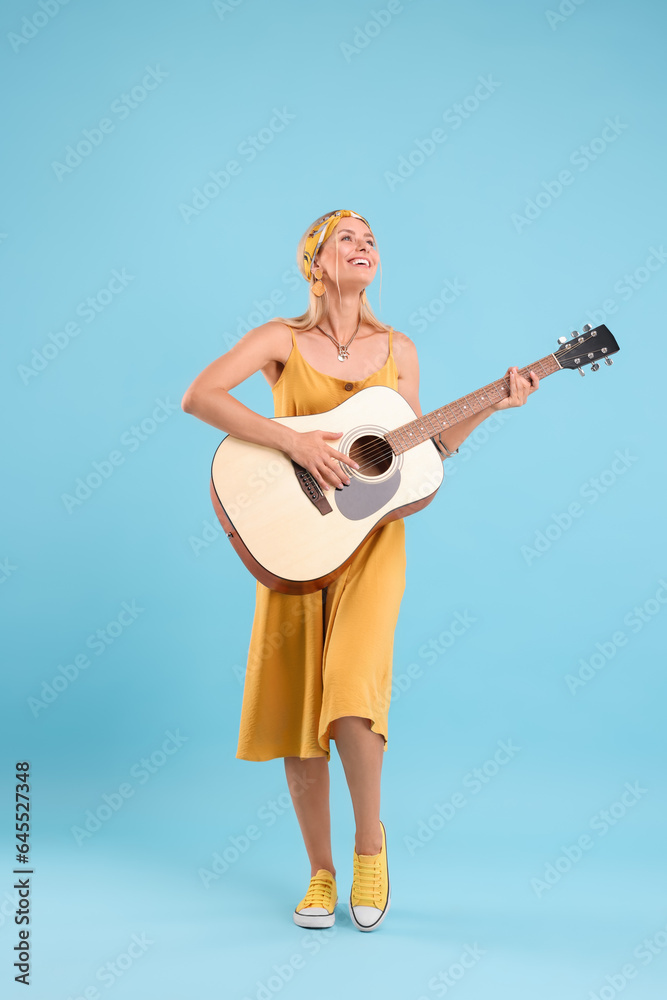 Happy hippie woman playing guitar on light blue background Happy hippie woman playing guitar on light blue background