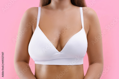 Woman with breast asymmetry on pink background, closeup