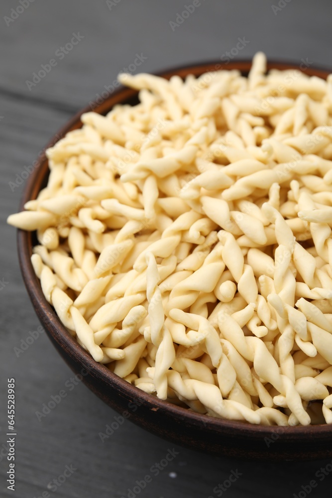 Uncooked trofie pasta in bowl on grey wooden table, closeup Uncooked trofie pasta in bowl on grey wooden table, closeup