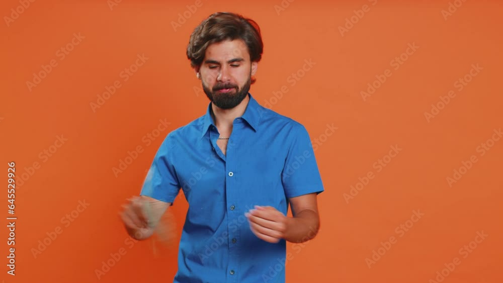 Rich pleased boss young man waving money dollar cash banknotes bills like a fan, success business career, lottery winner, big income, wealth. Middle eastern guy isolated on orange background, indoors