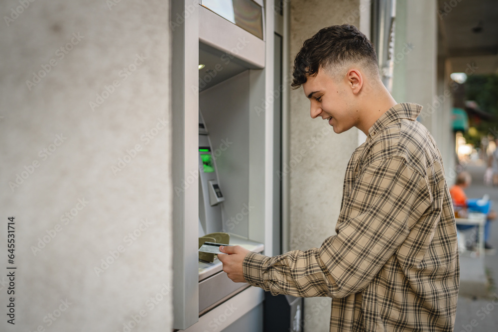 Fototapeta premium man teenage student using credit card and withdraw cash at the ATM