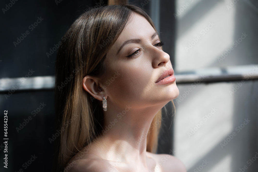 Beautiful young woman portrait in bright sunlight, contrast on the skin, bright highlights on the face
