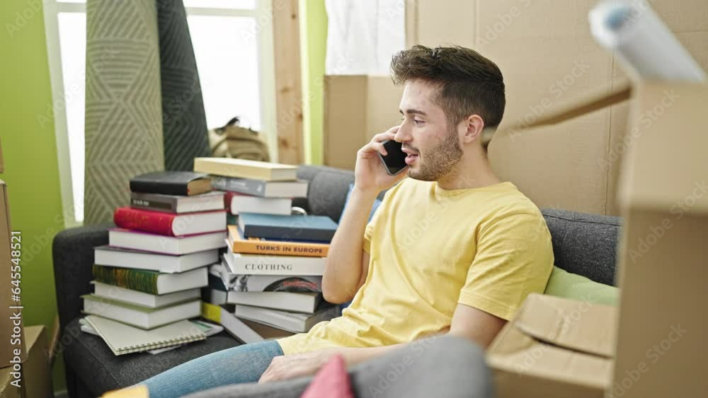 Young hispanic man talking on smartphone sitting on sofa at new home Young hispanic man talking on smartphone sitting on sofa at new home