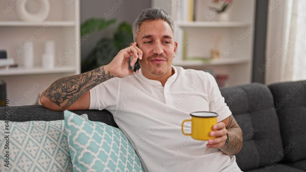 Young hispanic man talking on smartphone drinking coffee at home Young hispanic man talking on smartphone drinking coffee at home