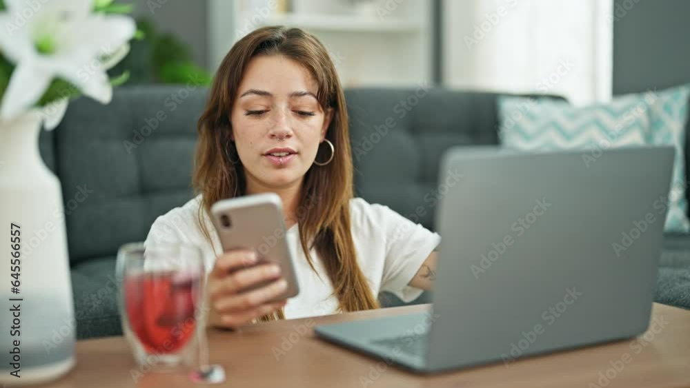 Young beautiful hispanic woman using laptop and smartphone sitting on floor at home Young beautiful hispanic woman using laptop and smartphone sitting on floor at home