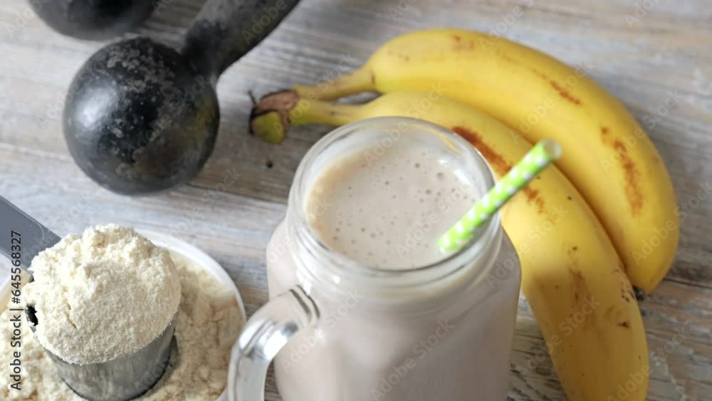 Protein drink, banana fruits, and dumbbells on a wooden background. Healthy eating and fitness concept. Protein drink, banana fruits, and dumbbells on a wooden background. Healthy eating and fitness concept.