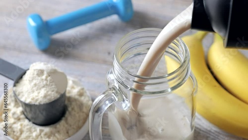 Pouring whey protein cocktail in a glass. Fitness and healthy lifestyle concept.
