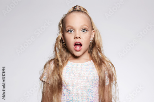 little girl in beautiful dress and make-up. Portrait of funny Child. Blonde