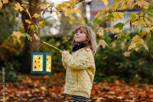 Little preschool kid girl holding selfmade traditional lanterns with candle for St. Martin procession. child happy about children and family parade in kindergarten. German tradition Martinsumzug photo