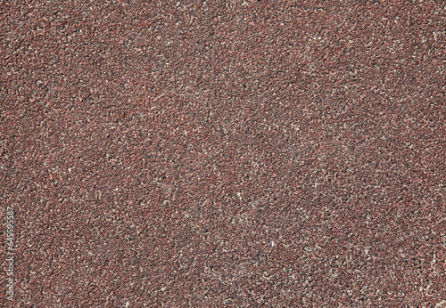 Red rubber floor, texture, background. Dusty and worn backdrop. Faded, old, granular rubber coating. Surface with blurry sand-filled chaotic pattern. Outdoor children playground equipment