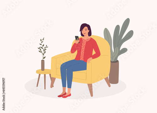 One Smiling Young Woman Sitting On Sofa While Using Her Mobile Phone. Full Length.