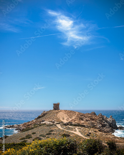 genoese tower protecting the corsican coast  with a large blue  sky with one white cloud