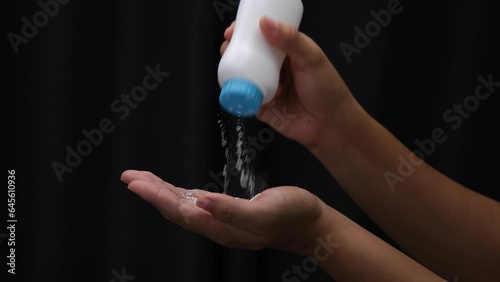 Female hand with talcum powder isolated on black background.
