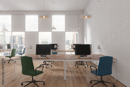 White office interior with pc monitors and desk near panoramic window