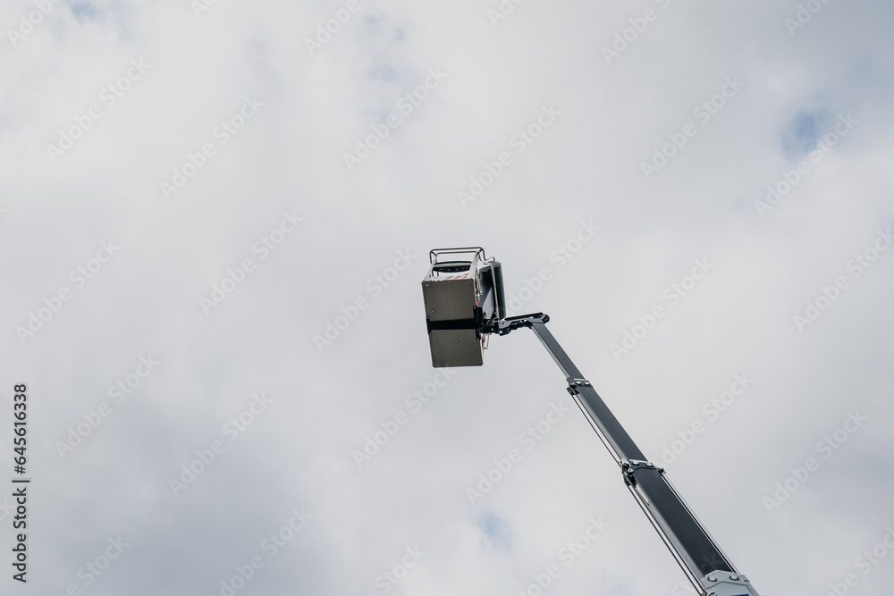 Construction lift basket elevated in the sky from below Construction lift basket elevated in the sky from below