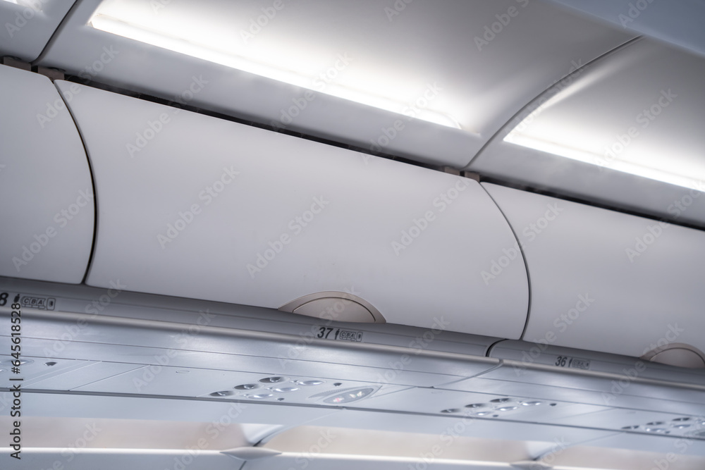 carry on luggage is stowed in overhead bins on a crowded airplane