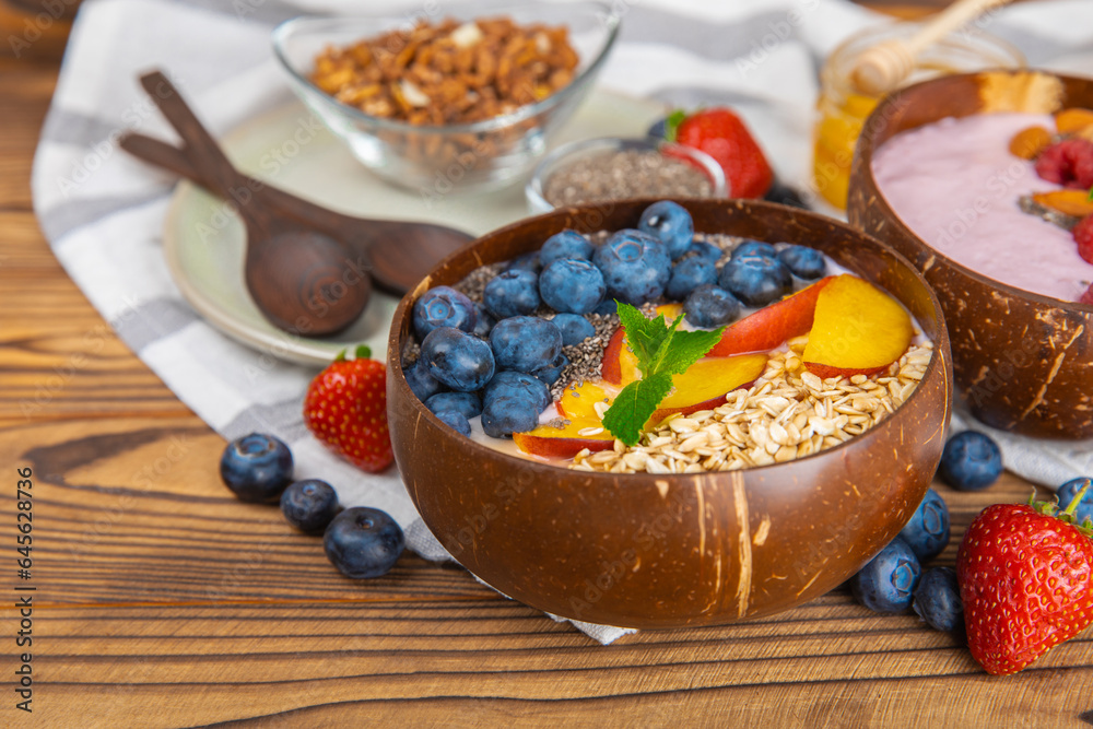 Bowl of granola with yogurt and fresh berries on a texture table. Yogurt berries, acai bowl, spirulina bowl. Healthy food, balanced breakfast. Strawberries, blueberries, kiwi, peach, almonds and chia. Bowl of granola with yogurt and fresh berries on a texture table. Yogurt berries, acai bowl, spirulina bowl. Healthy food, balanced breakfast. Strawberries, blueberries, kiwi, peach, almonds and chia.