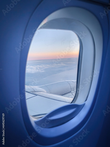 Airplane window with sunset view in orange.
